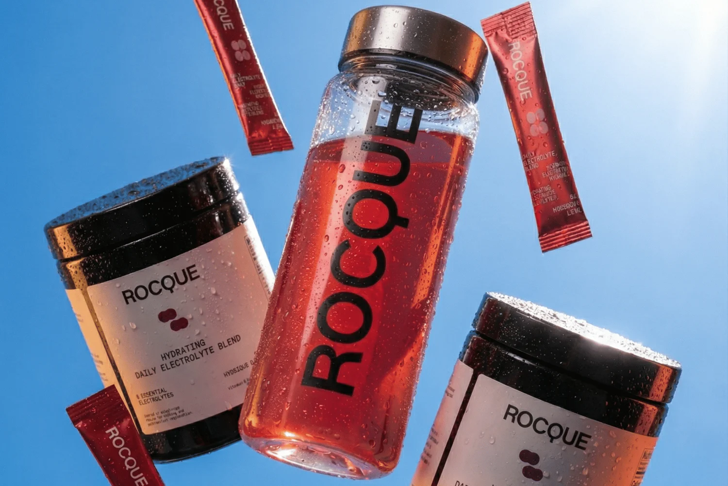 Rocque bottles, containers and sachets against a blue sky